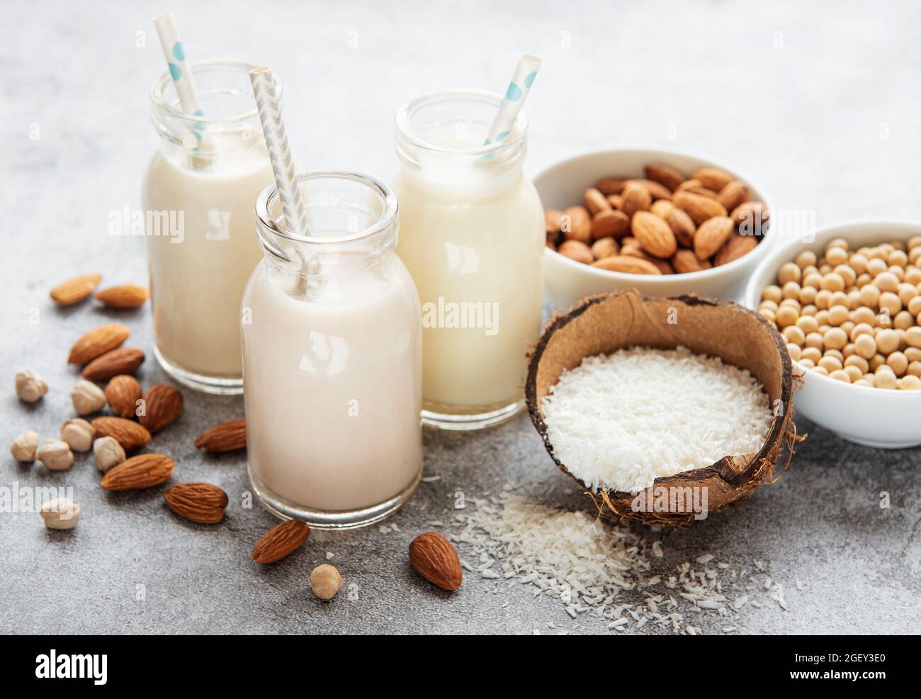 Alternative Arten von veganen Milchsorten in Glasflaschen auf betontem Hintergrund. Draufsicht Stockfoto