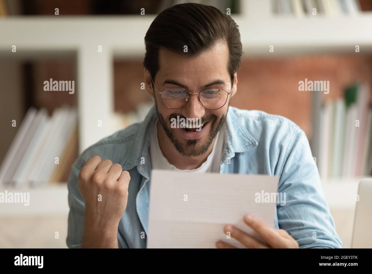 Der aufgeregt Mann, der den Postbrief liest, fühlt sich überglücklich über die guten Nachrichten Stockfoto