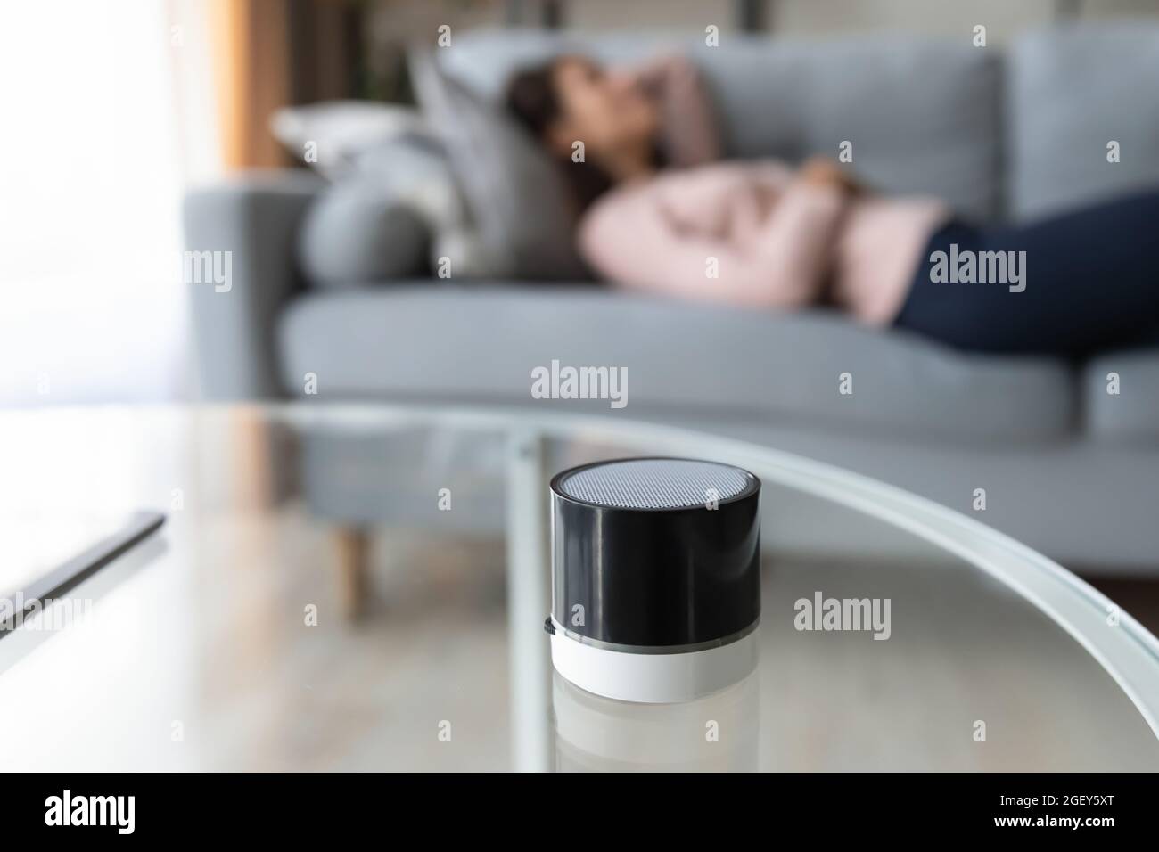 Frau liegt auf dem Sofa, Nahaufnahme konzentriert sich auf tragbare kabellose Lautsprecher Stockfoto