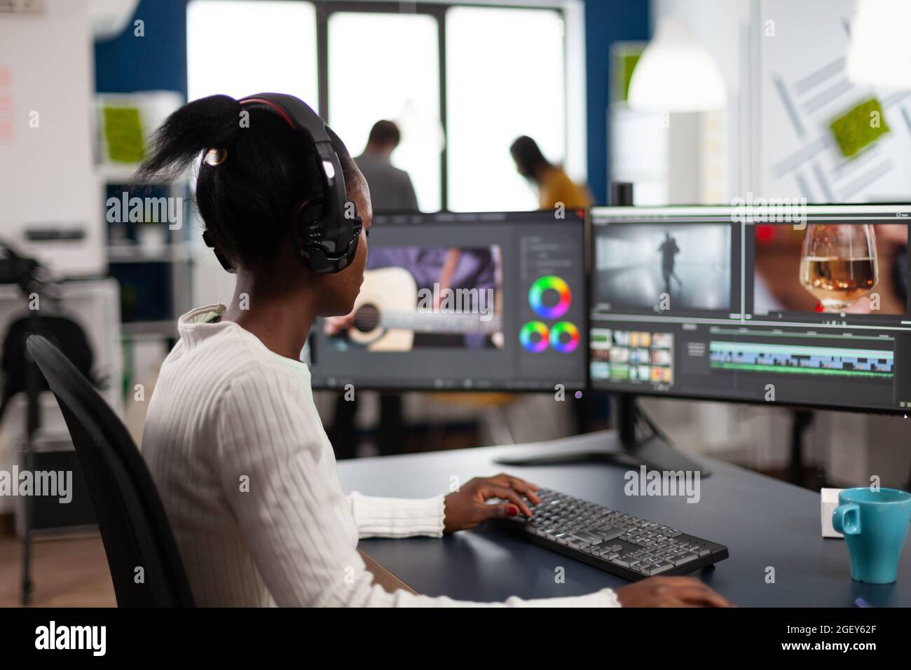 Schwarze Redakteurin, die bei der Projektfilmmontage arbeitet, sitzt im modernen Büro einer Kreativagentur. Videofilmer in digitalen Multimedia-Unternehmen Bearbeitung Film mit Post-Production-Software Stockfoto