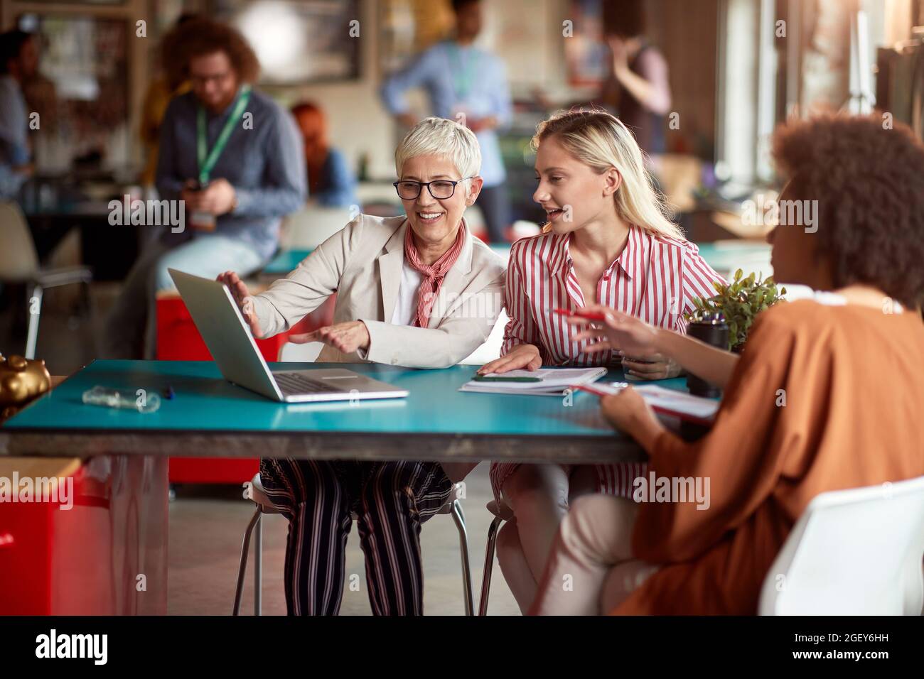 Leitender Manager aus dem kaukasus zeigt einem afroamerikanischen weiblichen Kunden zusammen mit einer jüngeren Kollegin einen Geschäftsplan auf einem Laptop Stockfoto