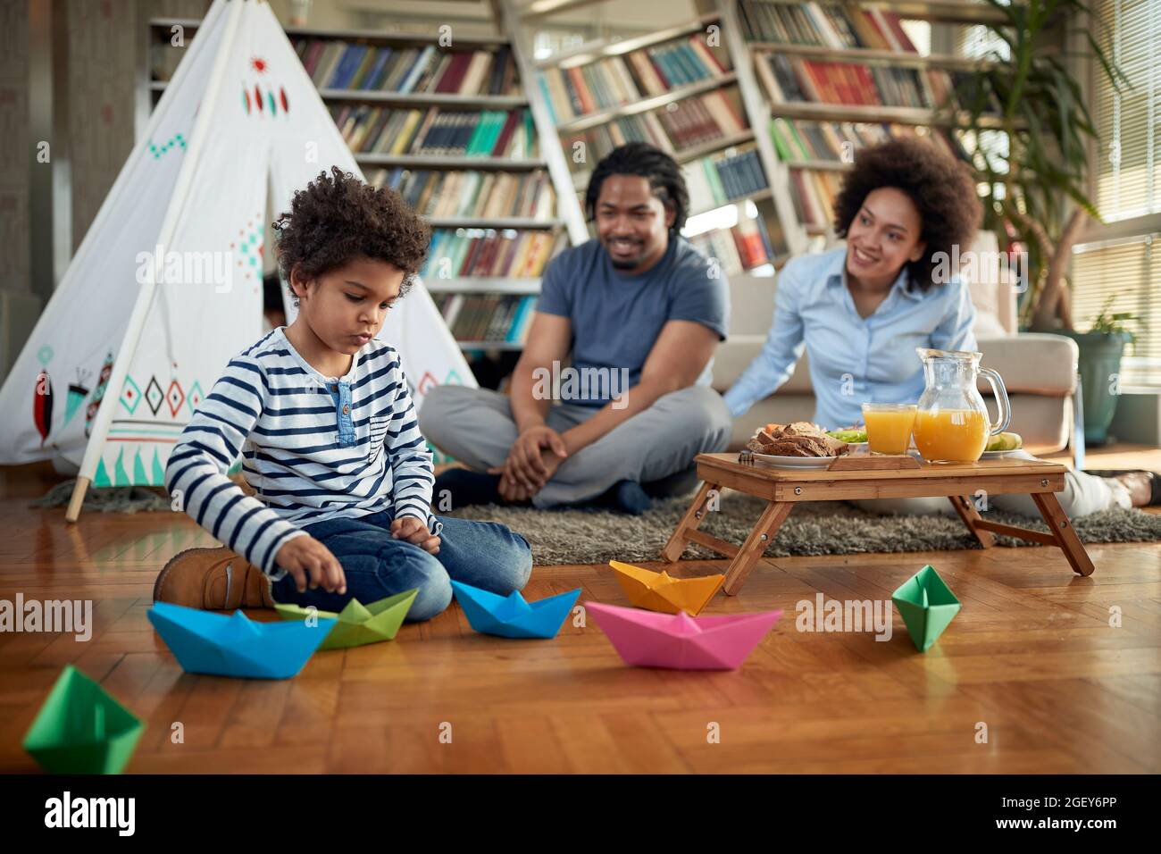 Junge Eltern verbringen gerne Zeit mit ihrem kleinen Jungen, während sie zu Hause in entspannter Atmosphäre spielen. Familie, Zuhause, zusammen, Spielzeit Stockfoto