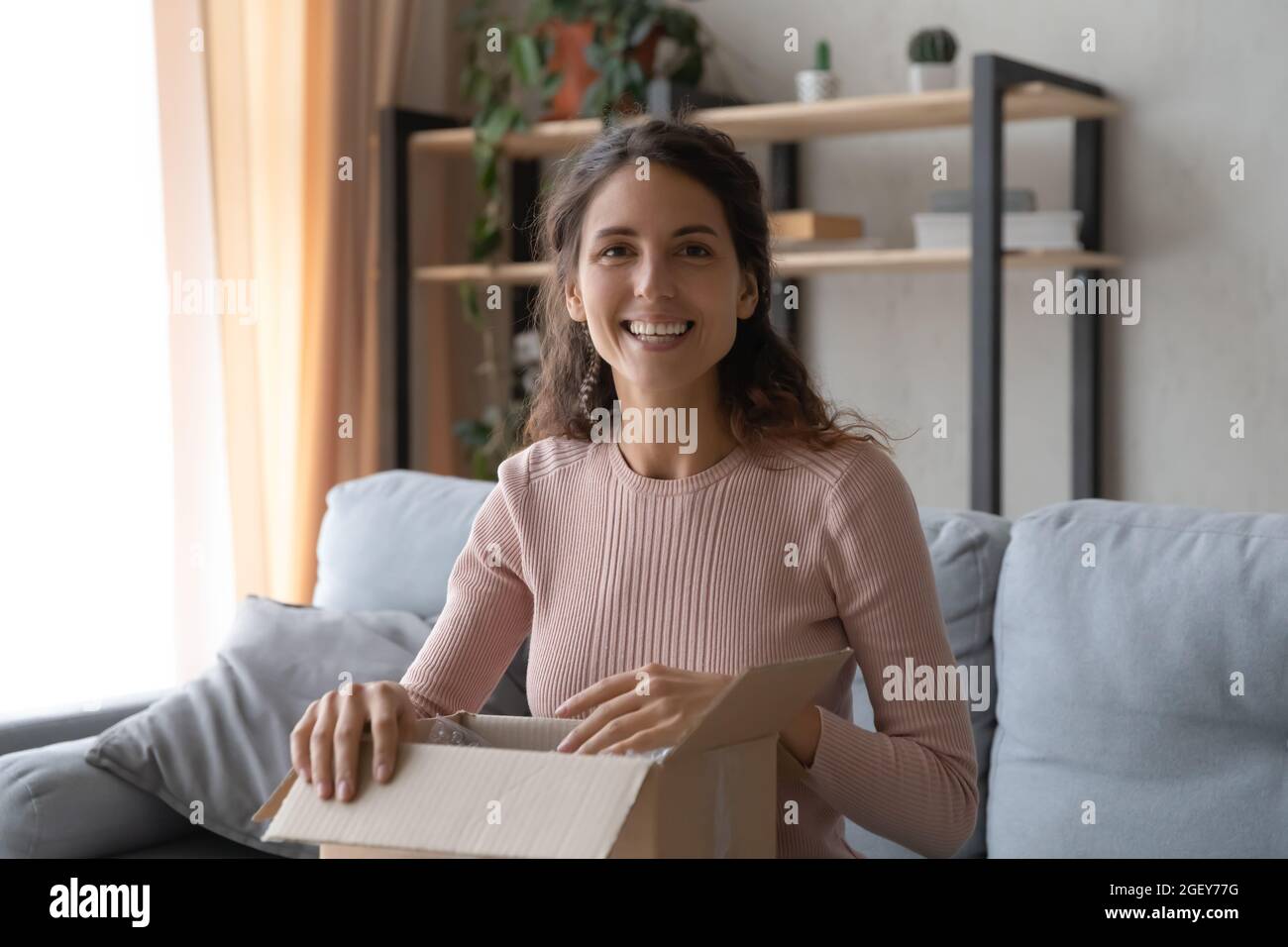 Frau, die den Paketkasten hält, fühlt sich mit den bestellten Waren zufrieden Stockfoto
