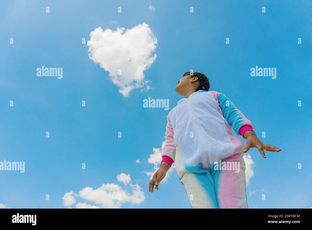 Eine Low-Angle-Aufnahme eines glücklichen hispanischen Jungen, der auf den blauen Himmel im Hintergrund blickt Stockfoto