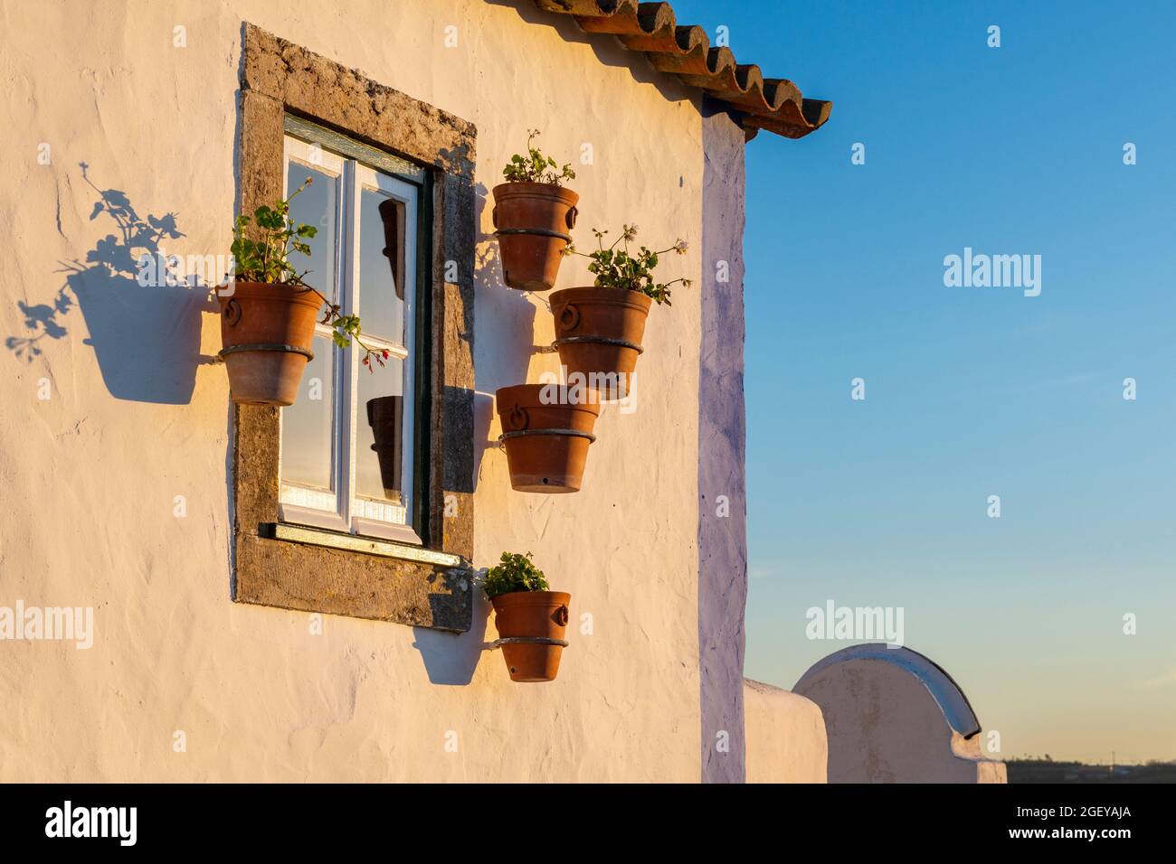Detail eines in Weiß und Blau gemalten traditionellen Hauses mit einem Fenster mit Keramikvasen in der Nähe von Mafra, Portugal. Stockfoto
