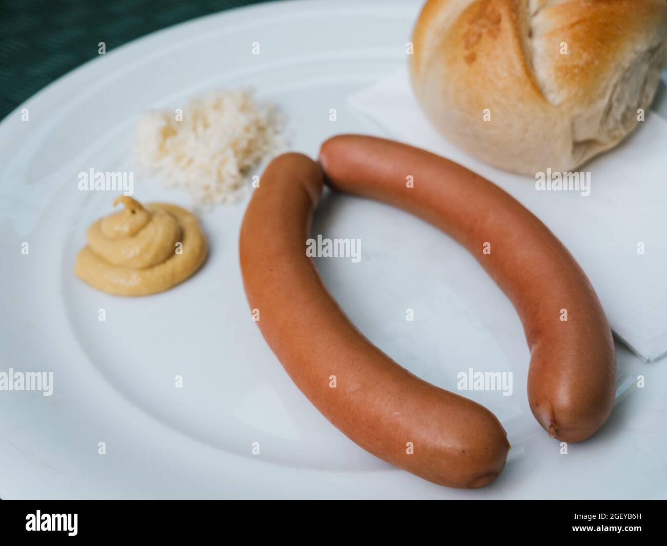 Frankfurter, Wiener oder Wiener Wurst mit Senf, Meerrettich und einer Kaiserrolle aus nächster Nähe Stockfoto
