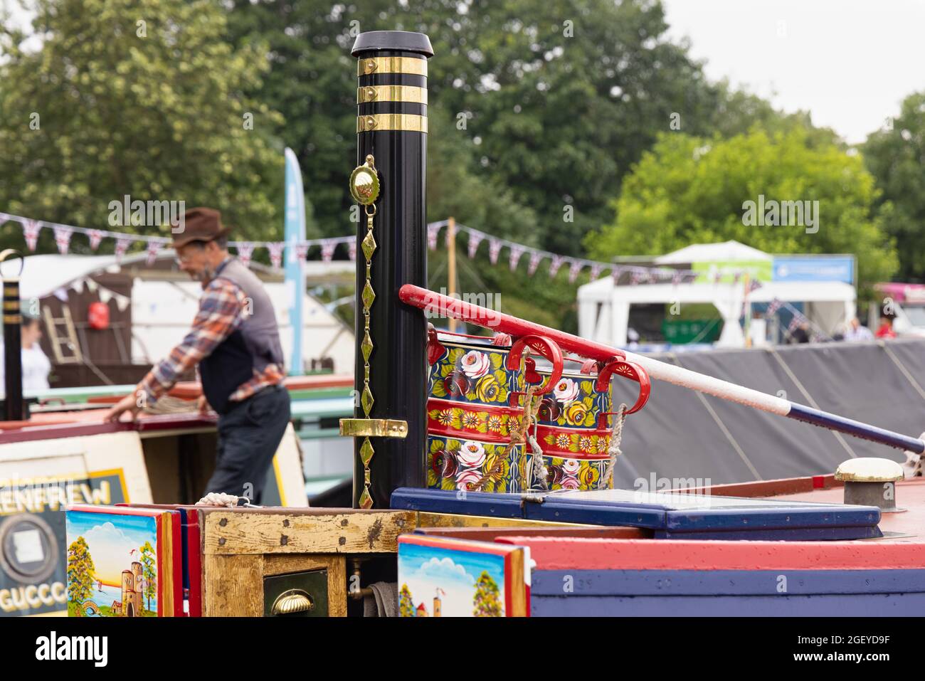 Crick, Northamptonshire, Großbritannien, 22. August 2021: Traditionell bemalte Krüge an einem mit Messing gebundenen Kamin auf dem Dach eines Schmalbootes auf der Crick Boatshow. Stockfoto