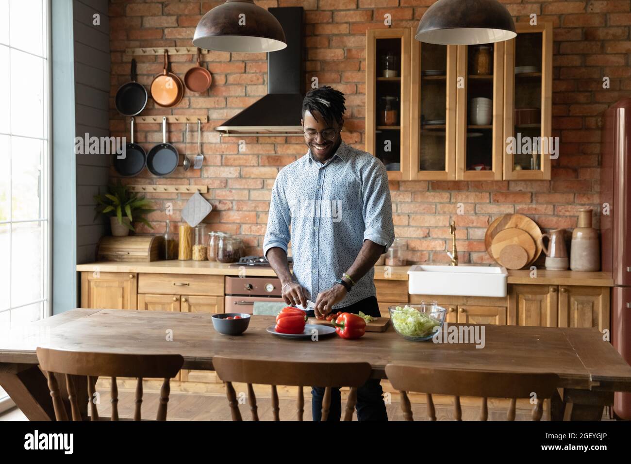 Happy Millennial African American Young man kocht Salat in der Küche Stockfoto