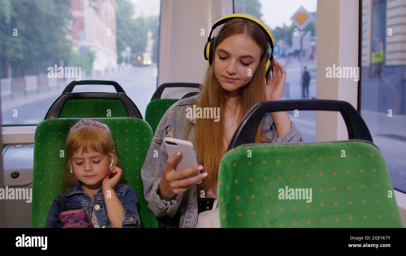 Kind Mädchen mit Mutter mit Smartphone mit Kopfhörern, Kopfhörer Musik hören, lustige Tänze Stockfoto