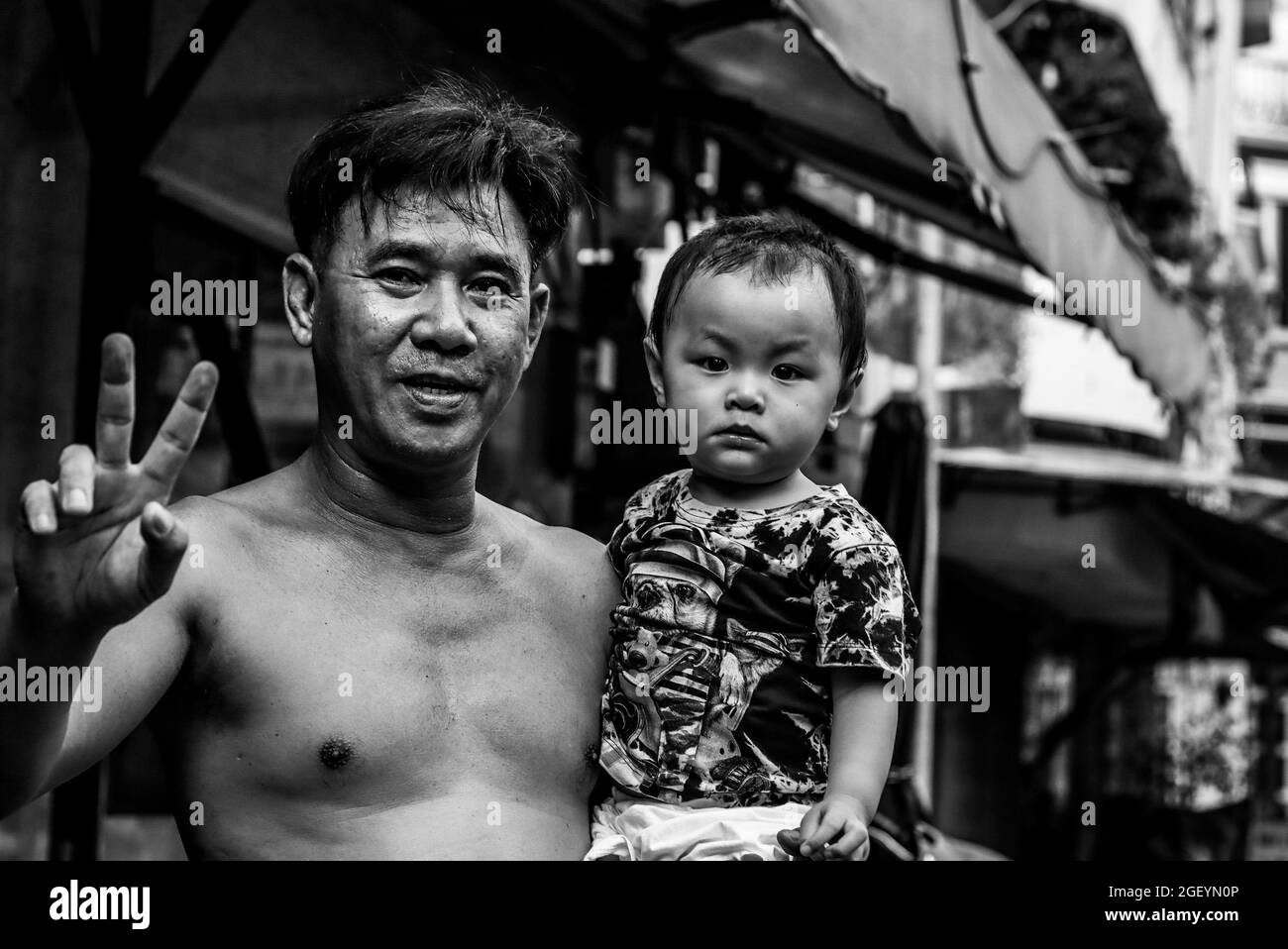 Vietnamesischer Mann mit seiner Tochter, gefangen genommen auf den Straßen von Saigon, Vietnam. (2021, Vor Covid) Stockfoto