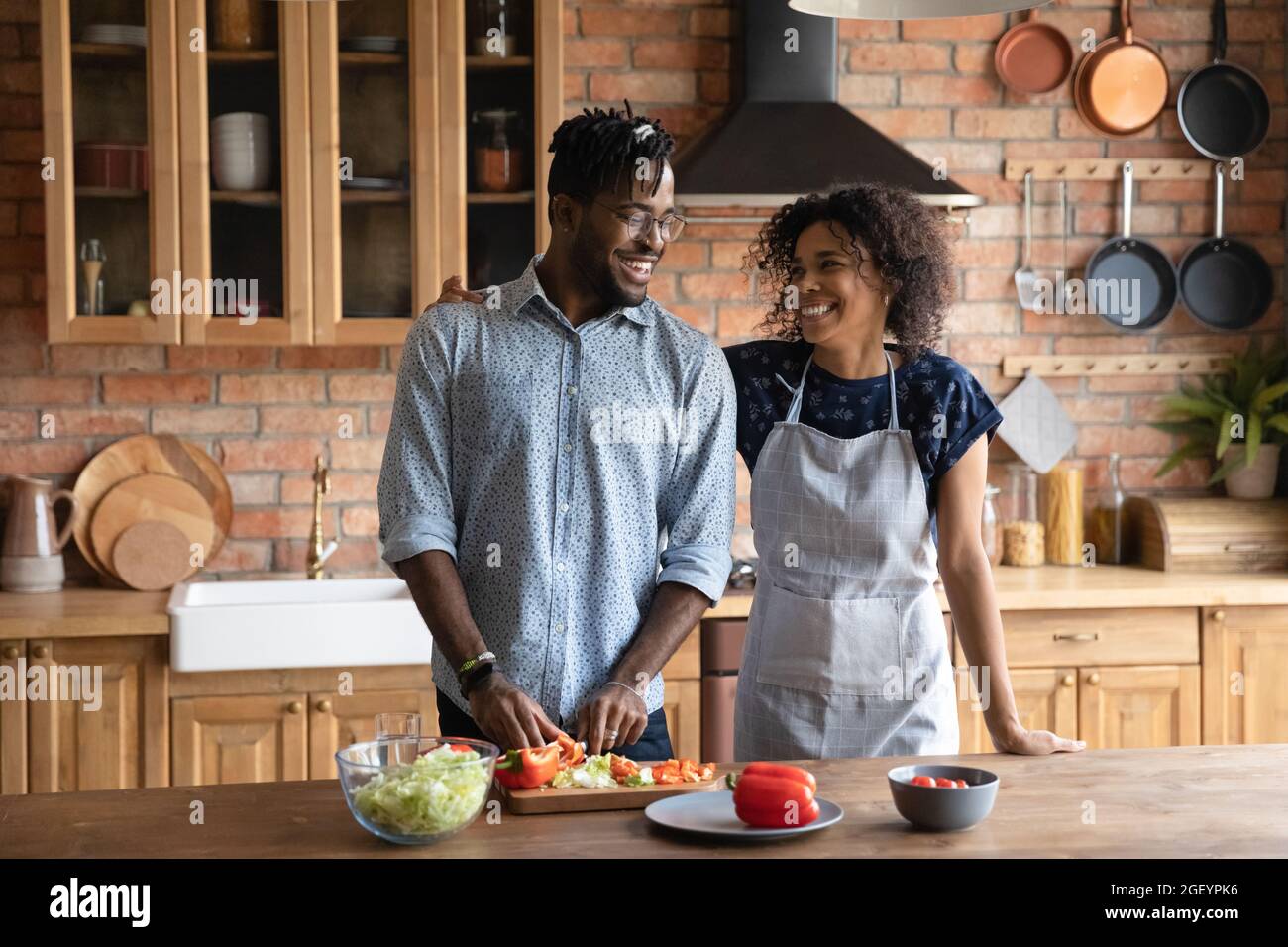Glückliches süßes afroamerikanisches Paar, das frischen Salat kocht Stockfoto