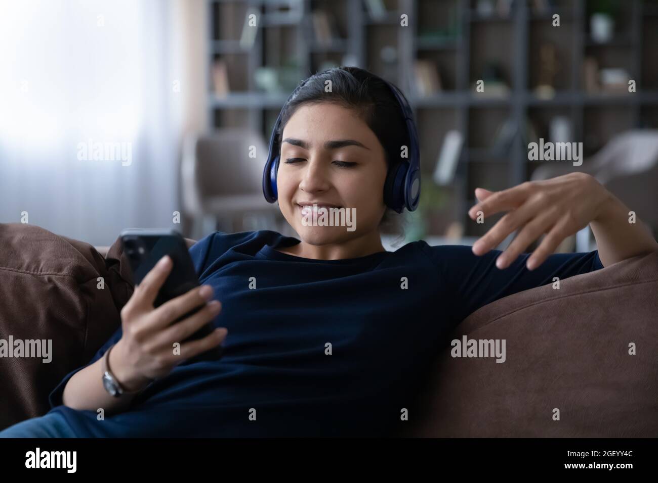 Glückliche indische Frau hört Musik auf dem Handy Stockfoto