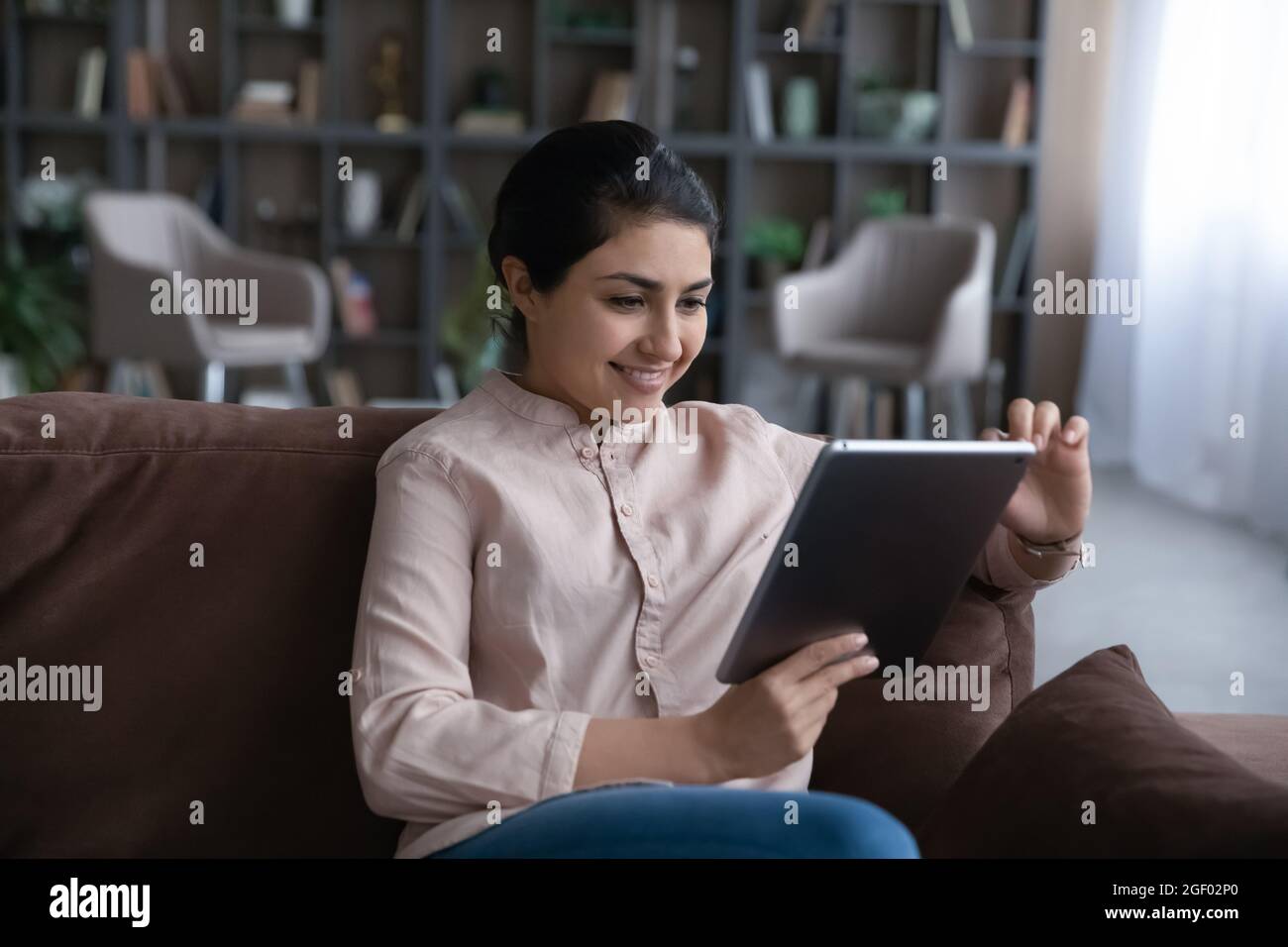 Lächelnde indische Frau verwenden Tablet zu Hause Stockfoto