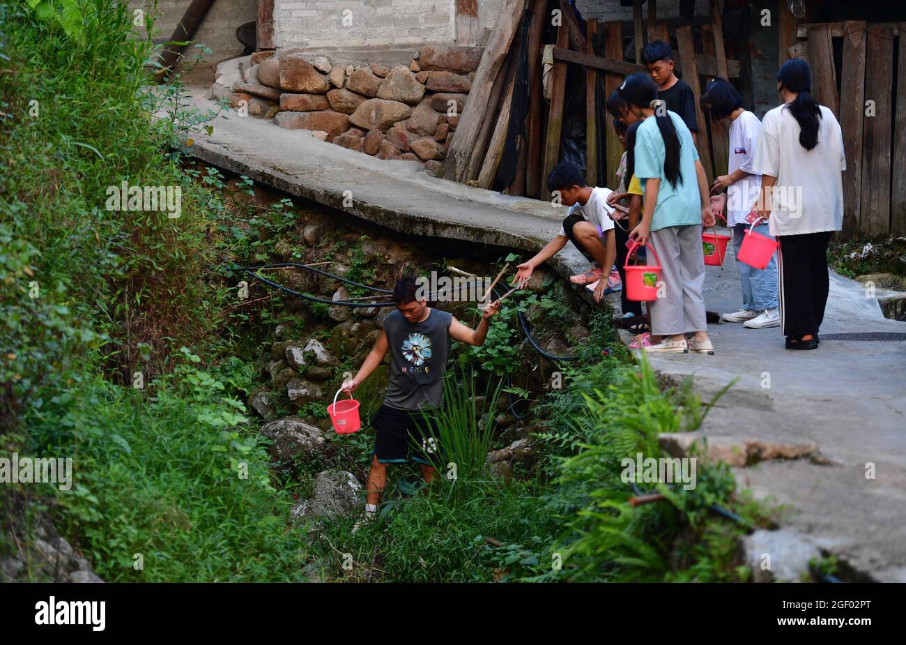 (210822) -- RONGSHUI, 22. August 2021 (Xinhua) -- Kollogestudent Pan Wenbo (1., L) reinigt am 20. August 2021 im Dorf Wuying, das an der Grenze zwischen der Autonomen Region Guangxi Zhuang im Süden Chinas und der Provinz Guizhou im Südwesten Chinas liegt, den Wasserlauf mit lokalen Studenten. Im Sommer 2021 führte ein ehrenamtliches Team aus Studenten und Mittelschülern lokale Schüler an verschiedenen Aktivitäten wie der Pflege von Setzlingen, dem Lernen über immaterielle Kulturgüter und dem Sammeln alter Bauernwerkzeuge für Museen Teil. (Xinhua/Huang Xiaobang) Stockfoto