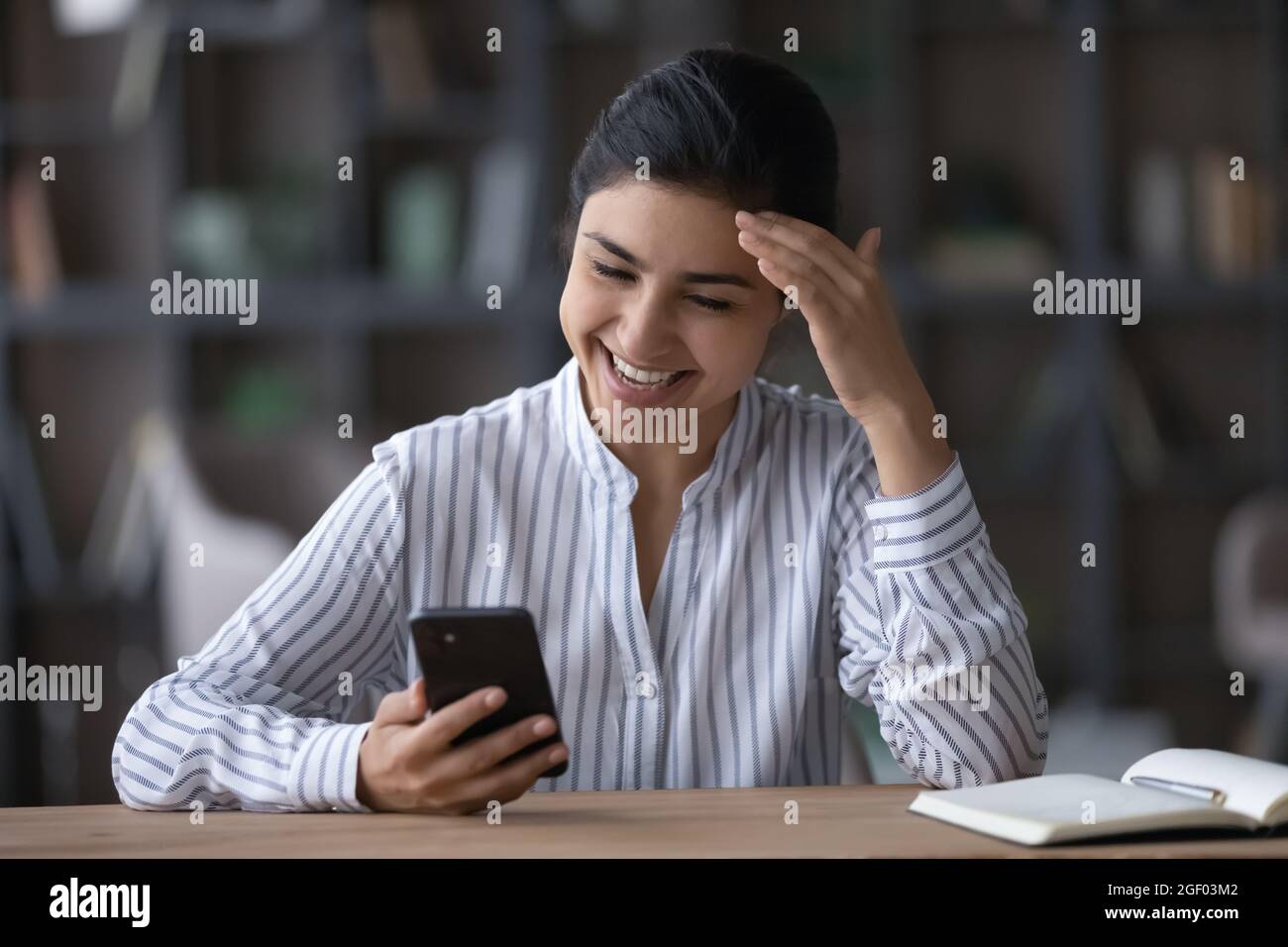 Lächelnde indische Frau verwenden Handy-SMS lachend Stockfoto