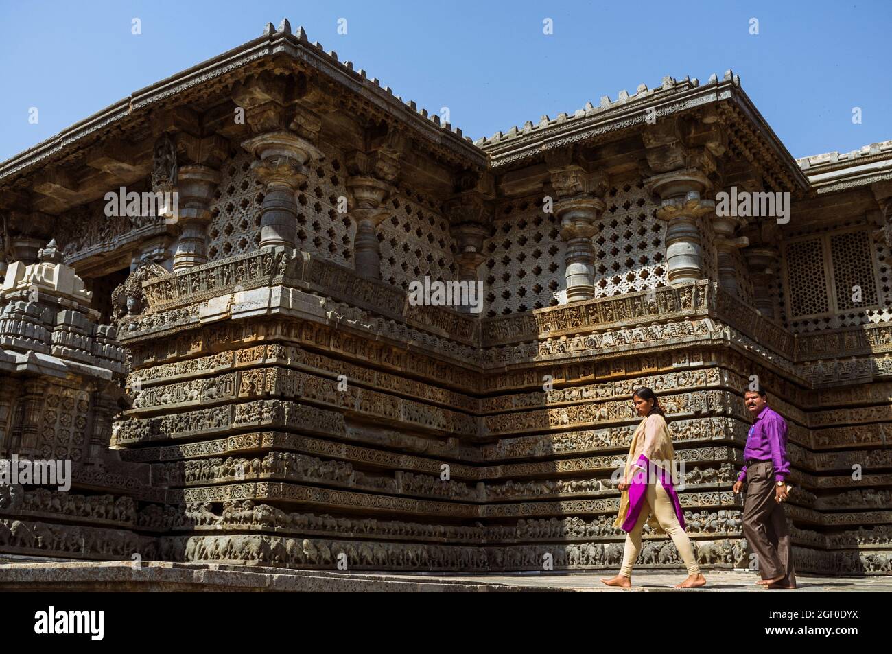 Halebid, Karnataka, Indien: EIN Mann und eine Frau gehen um den Hoysaleswara-Tempel aus dem 12. Jahrhundert Stockfoto