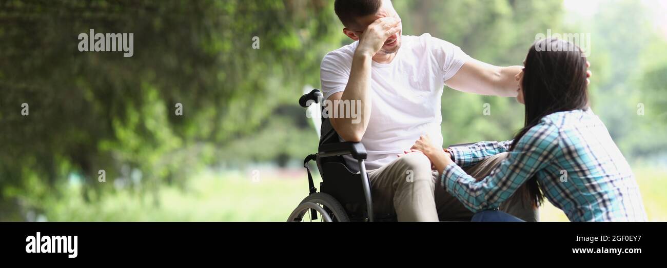 Behinderter Mann im Rollstuhl kommuniziert mit der Frau im Park Stockfoto