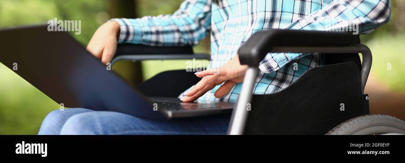 Frau im Rollstuhl auf den Knien mit Laptop Stockfoto