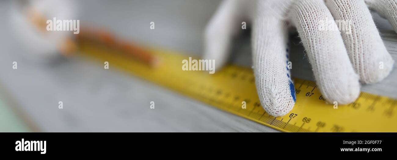 Hände des Meisters, die mit einem Lineal auf Laminat messen Stockfoto