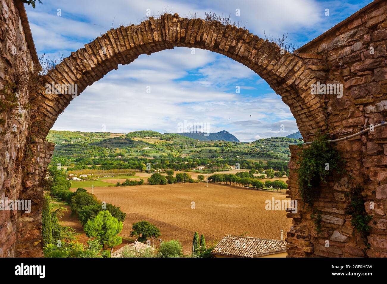 Blick auf die Landschaft Umbriens durch den Steinbogen des historischen Zentrums von Spello Stockfoto