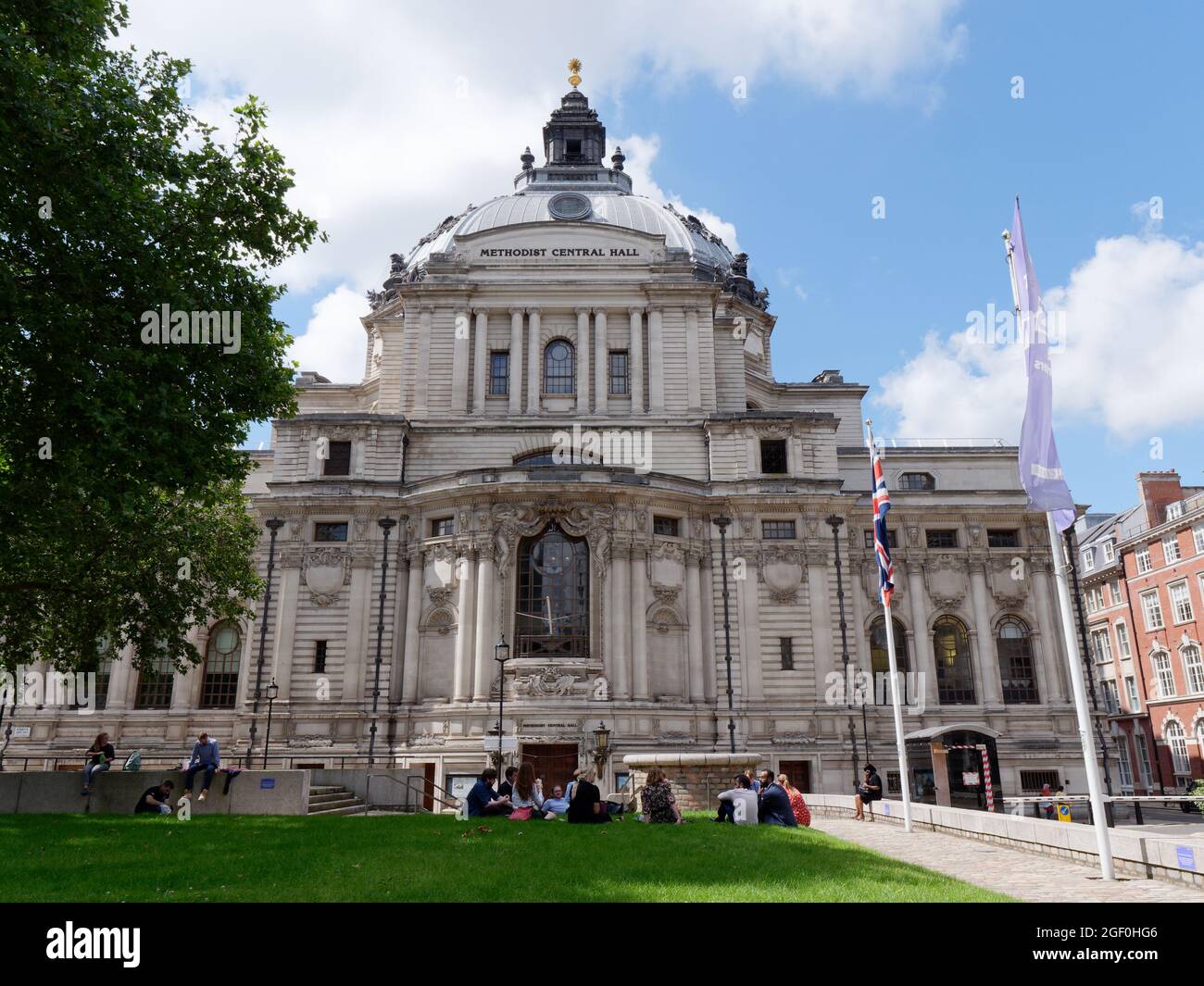 London, Greater London, England, 10 2021. August: Eine Gruppe sitzt auf dem Green der Vereinten Nationen vor der Central Hall Westminster, auch Methodist Central Hall genannt. Stockfoto