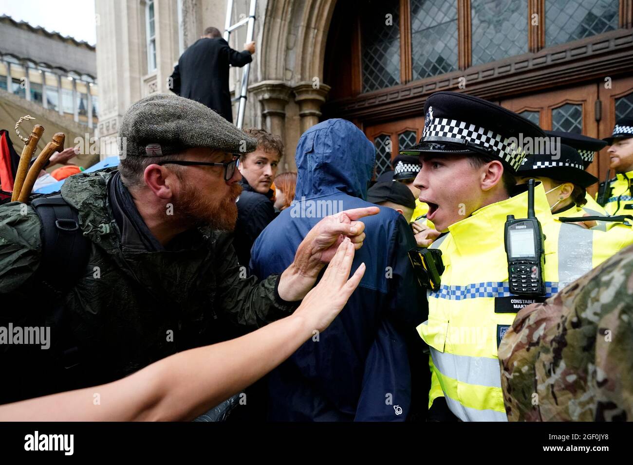 Ein Mann zeigt auf einen Polizisten, während Mitglieder der Extinction Rebellion vor der Guildhall in London protestieren. Bilddatum: Sonntag, 22. August 2021. Stockfoto