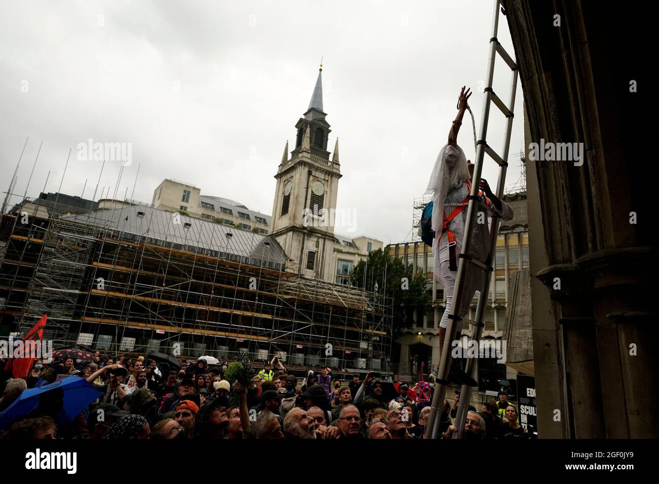 Ein Mann klettert eine Leiter, während Mitglieder der Extinction Rebellion vor der Guildhall in London protestieren. Bilddatum: Sonntag, 22. August 2021. Stockfoto