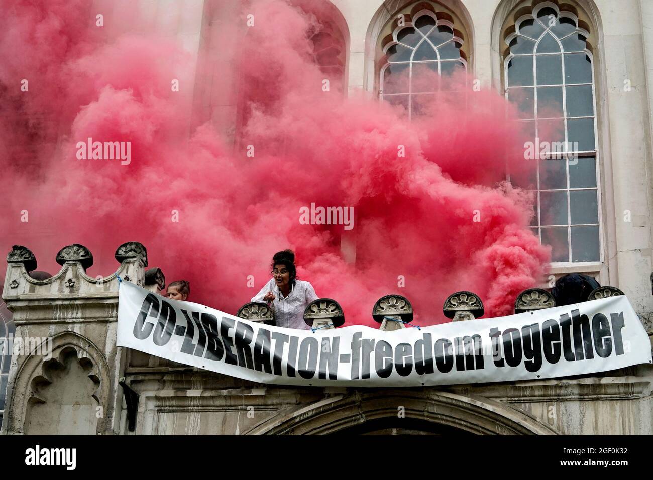 Menschen lassen Fackeln los und entrollen ein Banner von einem Vorsprung über dem Eingang zur Guildhall in London, während die Extinction Rebellion einen Protest ausführt. Bilddatum: Sonntag, 22. August 2021. Stockfoto