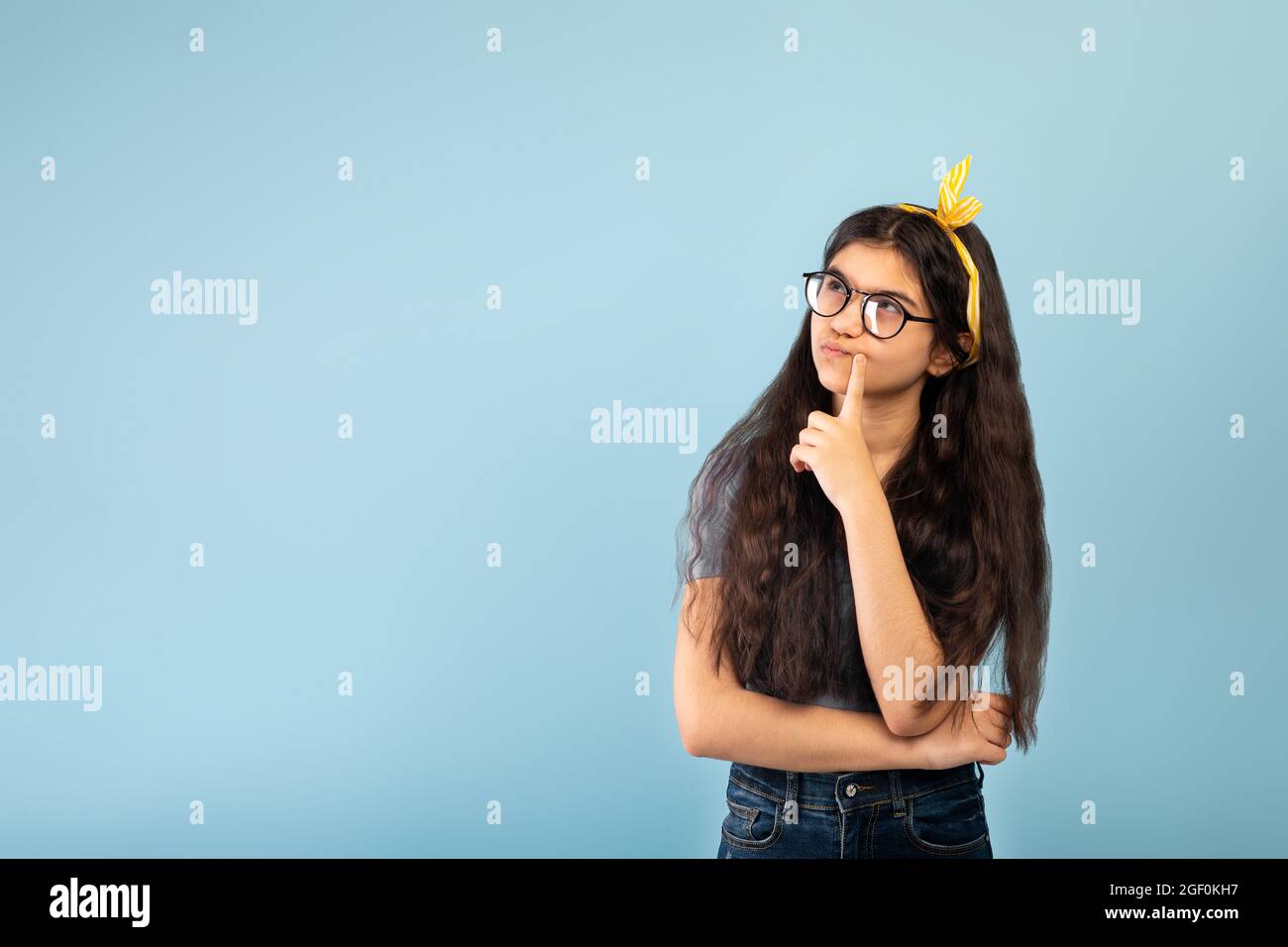 Nachdenkliche indische Teenager-Mädchen in Freizeitkleidung Blick auf Kopie Raum über blauen Studio-Hintergrund Stockfoto