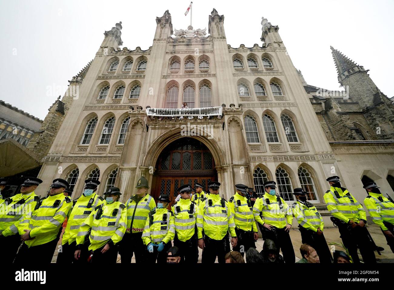 Polizeibeamte bilden eine Linie vor dem Eingang zur Guildhall in London, wo Demonstranten während einer Aussterbungsrebellion, die einen Protest ausführte, auf einen Vorsprung über dem Eingang geklettert sind. Bilddatum: Sonntag, 22. August 2021. Stockfoto