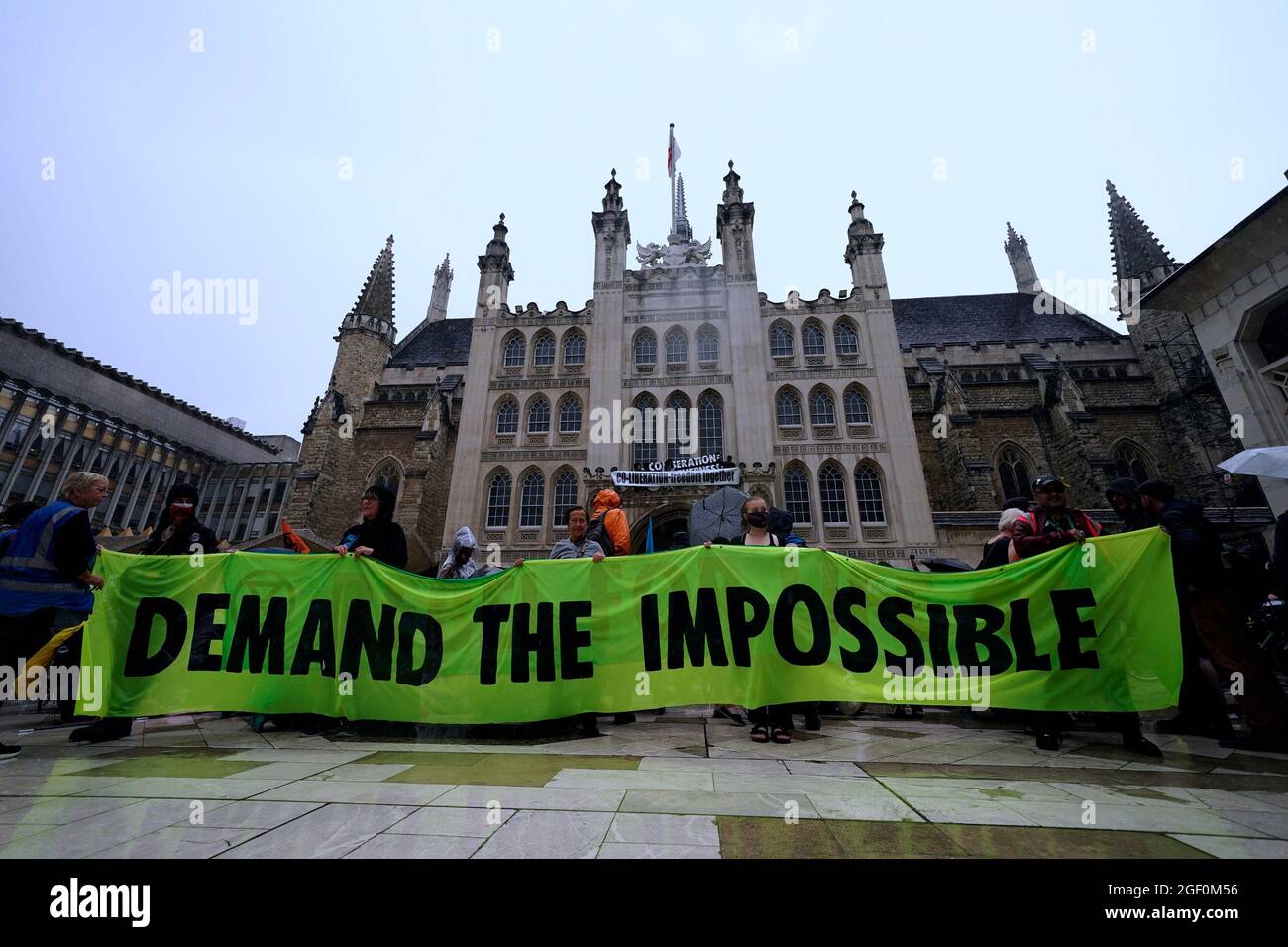 Menschen halten ein Banner vor dem Eingang zur Guildhall in London, wo Demonstranten während eines Protestes der Extinction Rebellion auf eine Kante über dem Eingang geklettert sind. Bilddatum: Sonntag, 22. August 2021. Stockfoto