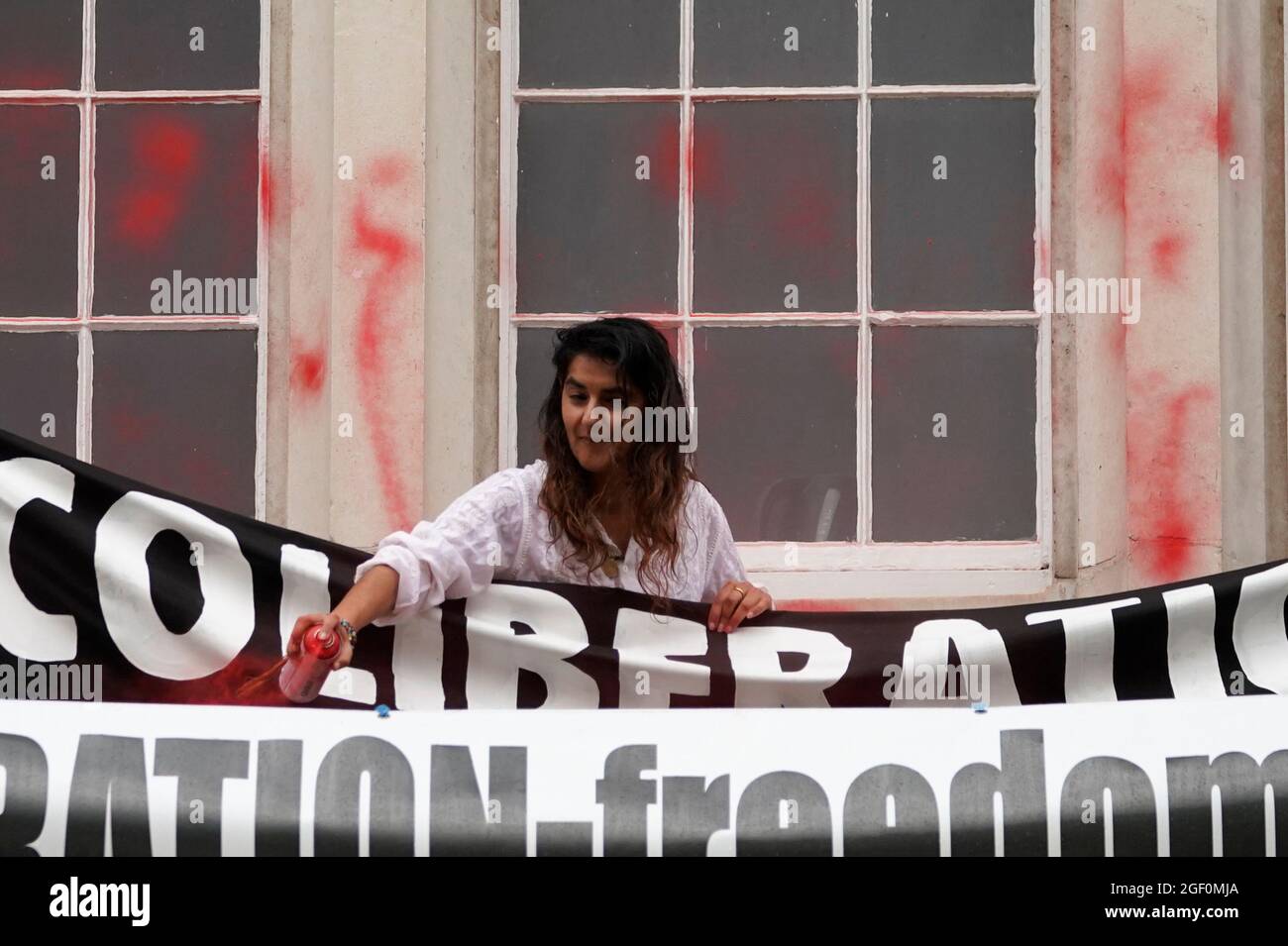 Eine Frau sprüht während eines Protestes von Mitgliedern der Extinction Rebellion rote Farbe auf die Außenseite der Guildhall in London. Bilddatum: Sonntag, 22. August 2021. Stockfoto