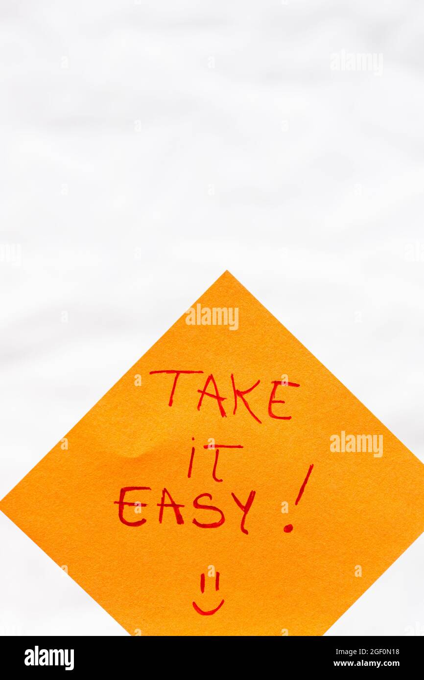 Ein handschriftlicher Text mit der Aufschrift „Take it easy“ auf einem orangefarbenen Papier Stockfoto