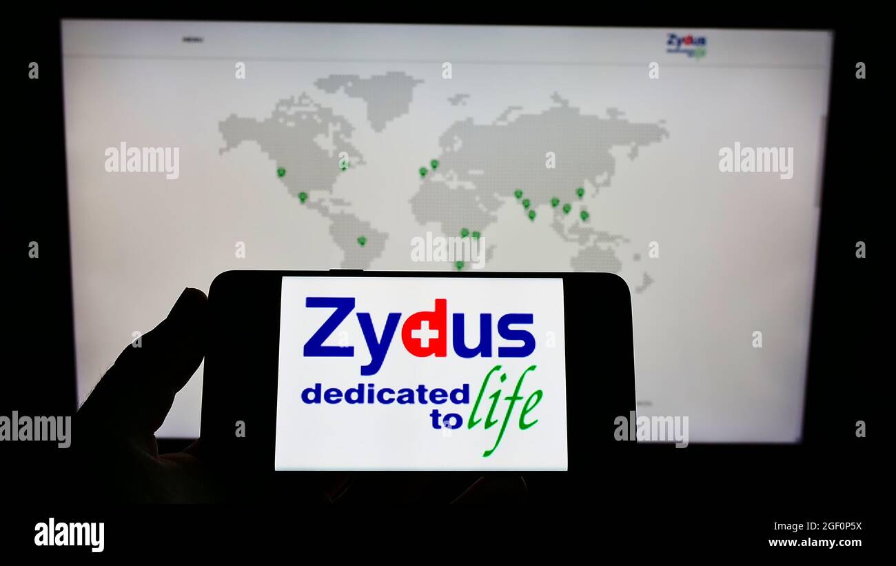 Person, die das Smartphone mit dem Logo des indischen Unternehmens (Zydus) Cadila Healthcare Limited auf dem Bildschirm vor der Website hält. Konzentrieren Sie sich auf die Telefonanzeige. Stockfoto
