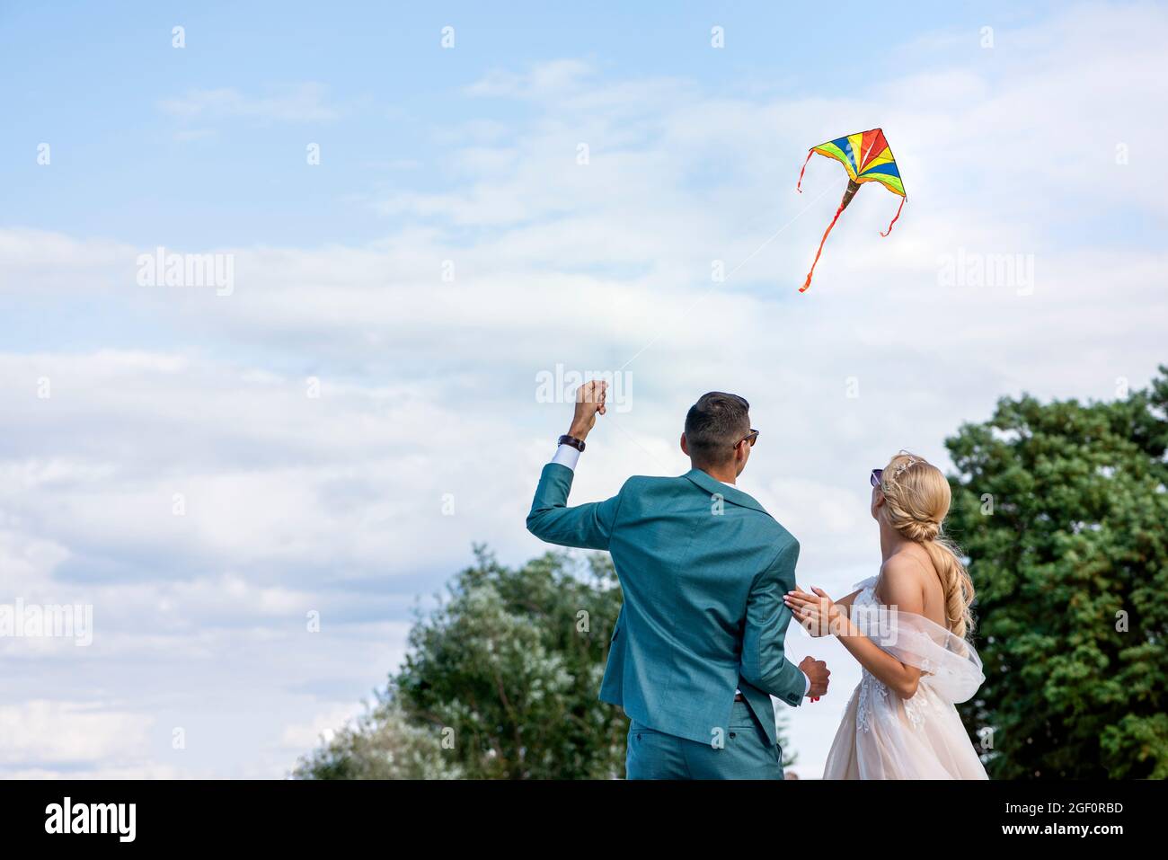 Ein Drachen bei einer Hochzeit. Ein Hochzeitspaar bringt einen Drachen in den Himmel. Braut und Bräutigam fliegen an ihrem Hochzeitstag einen Drachen zusammen. Stockfoto