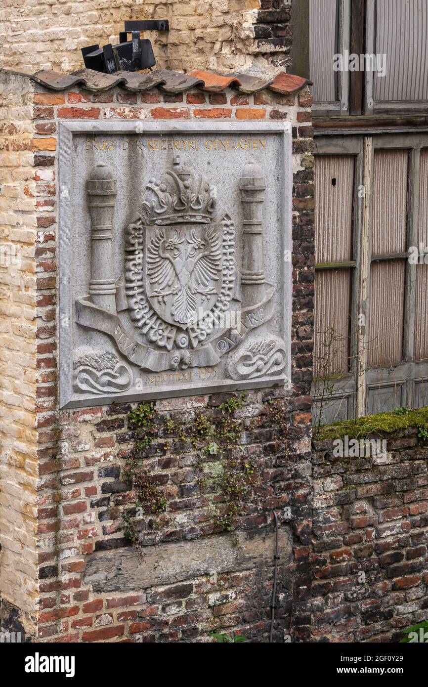 Gent, Flandern, Belgien - 30. Juli 2021: Nahaufnahme des grauen Steinwappens Kaiser Karl V. in roter Ziegelmauer bei Brug der Keizerlijke Geneugten Stockfoto