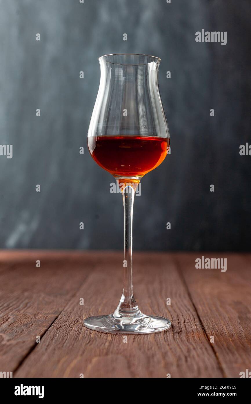 Grappa-Glas mit Brandy oder Sherry oder Calvados auf Holztisch. Stockfoto