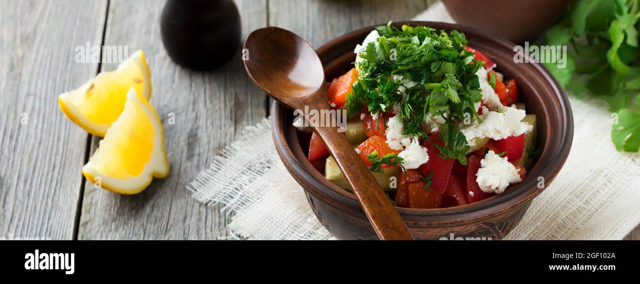 Frischer Salat aus gebackenen Paprika, Tomaten, Zwiebeln, Gurken, Petersilie, Dill und Fetakäse in einer Keramikschale. Traditionelle serbische Küche. Selektive Stockfoto