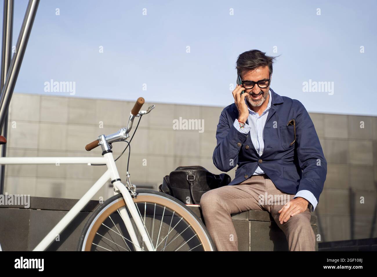 Erwachsene Männer, die am Telefon sitzen und das Fahrrad an der Wand  lehnen. Ökologisches Transportkonzept. Hochwertige Fotos Stockfotografie -  Alamy