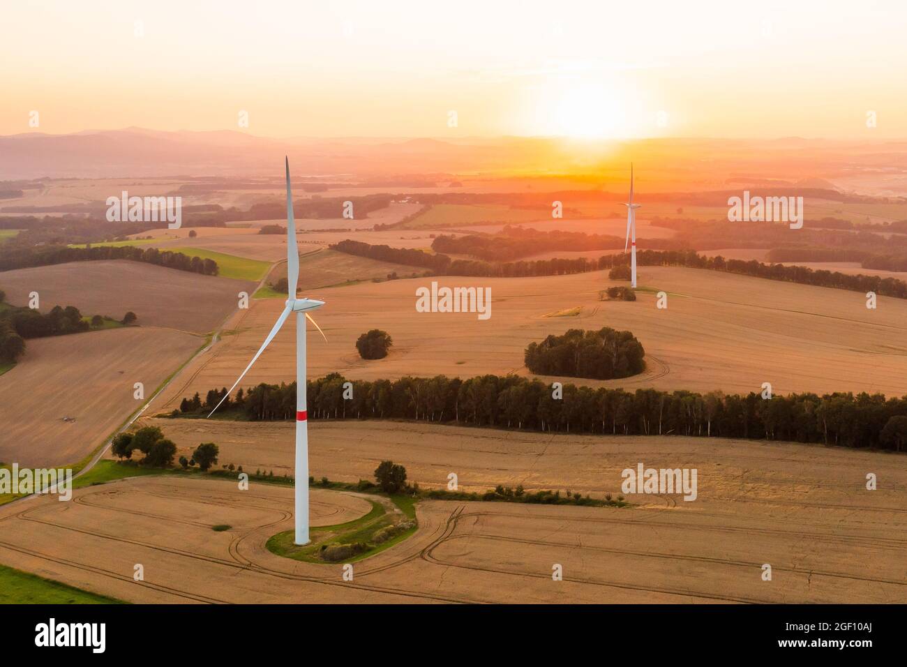 Panoramablick auf Windmühlen oder Windkraftanlagen für die Stromerzeugung bei herrlichem Sonnenuntergang auf dem Feld. Umweltfreundliche Erzeugung erneuerbarer Energien. Stockfoto