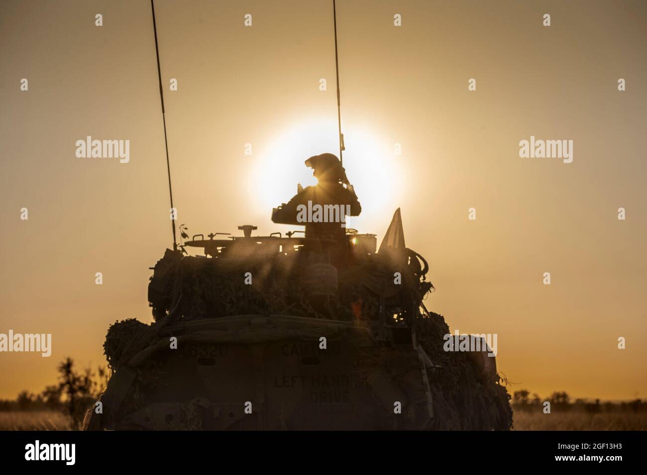 Bradshaw Station, Australien. August 2021. Ein Soldat der australischen Armee mit dem 1. Panzerregiment wird während einer Live-Feuerübung im Bradshaw Field Training Area am 21. August 2021 in Bradshaw Station, NT, Australien, von der Sonne im Turm eines Australian Service Light Armored Vehicle silhouettiert. Quelle: Planetpix/Alamy Live News Stockfoto