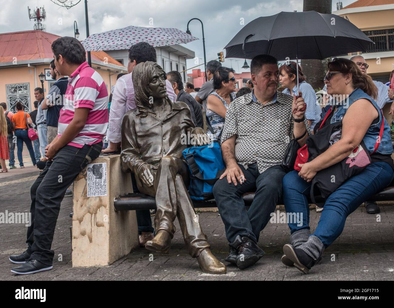 Menschen, die neben einer Bronzestatue von John Lennon in San Jose, Costa Rica, sitzen. Stockfoto
