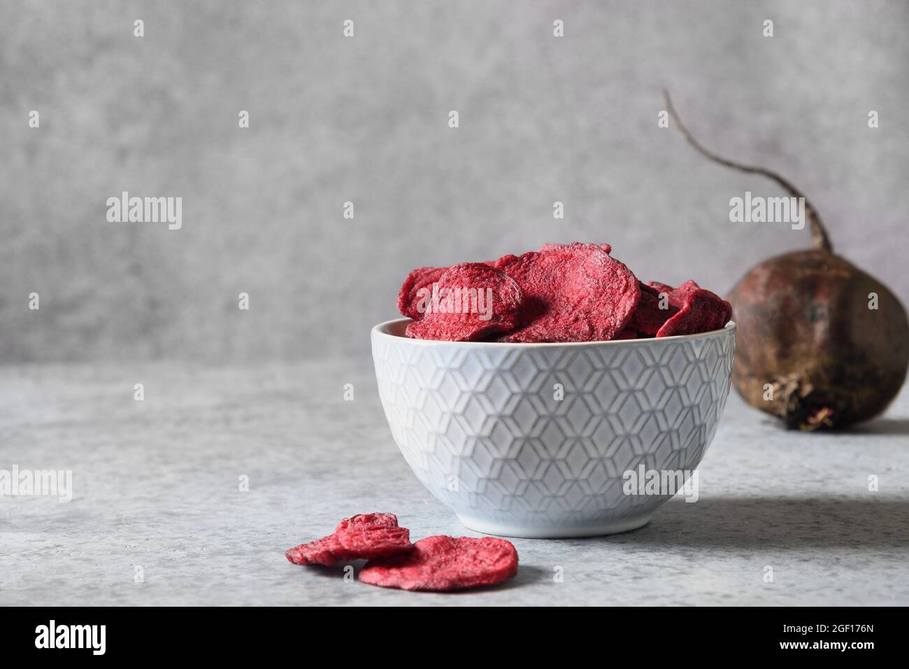 Vegetarische vegane Rote-Beete-Chips in Schale auf grauem Hintergrund. Veganer Snack. Nahaufnahme. Heimtrocknung. Stockfoto