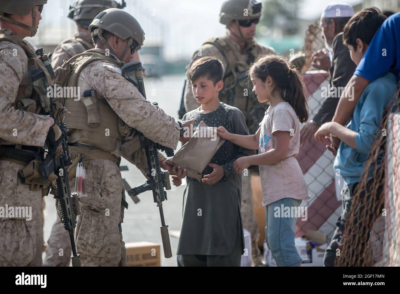 Kabul, Afghanistan. August 2021. Eine US-Marine mit dem Special Purpose Marine Air-Ground Task Force/Crisis Response Team hilft beim Öffnen von MRE für afghanische Kinder am Hamid Karzai International Airport während der Operation Allies Refuge am 21. August 2021 in Kabul, Afghanistan. Quelle: Planetpix/Alamy Live News Stockfoto