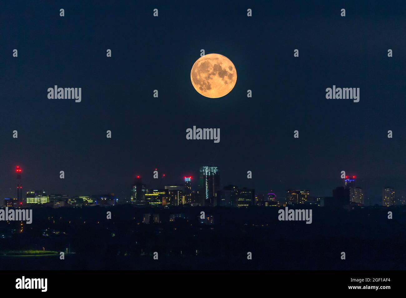 Birmingham, Großbritannien. August 2021. Der Vollmond hängt wie eine riesige Lampe über den Lichtern der Stadt Birmingham, Großbritannien. Dieser August-Vollmond wird den Spitznamen „turgeon“-Mond erhalten. Kredit: Peter Lopeman/Alamy Live Nachrichten Stockfoto