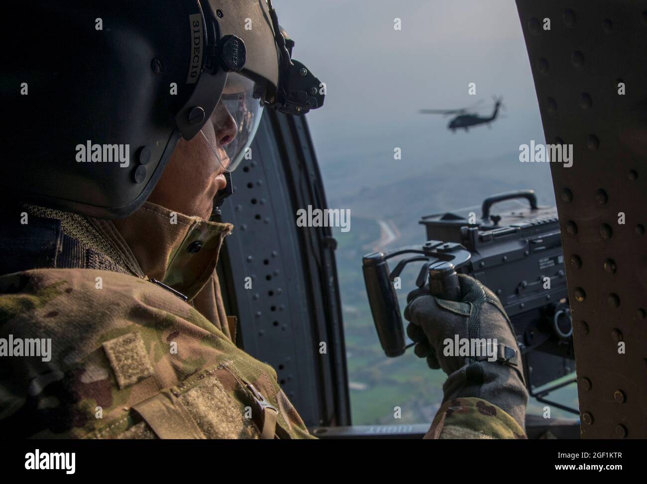 Ein US-Soldat, der der 10th Mountain Division zugewiesen wurde, untersucht die Seite eines UH-60 Black Hawk während eines Fluges über Zentralafghanistan am 30. November 2019. (USA Army Reserve Foto von SPC. Jeffery J. Harris/ veröffentlicht) Stockfoto