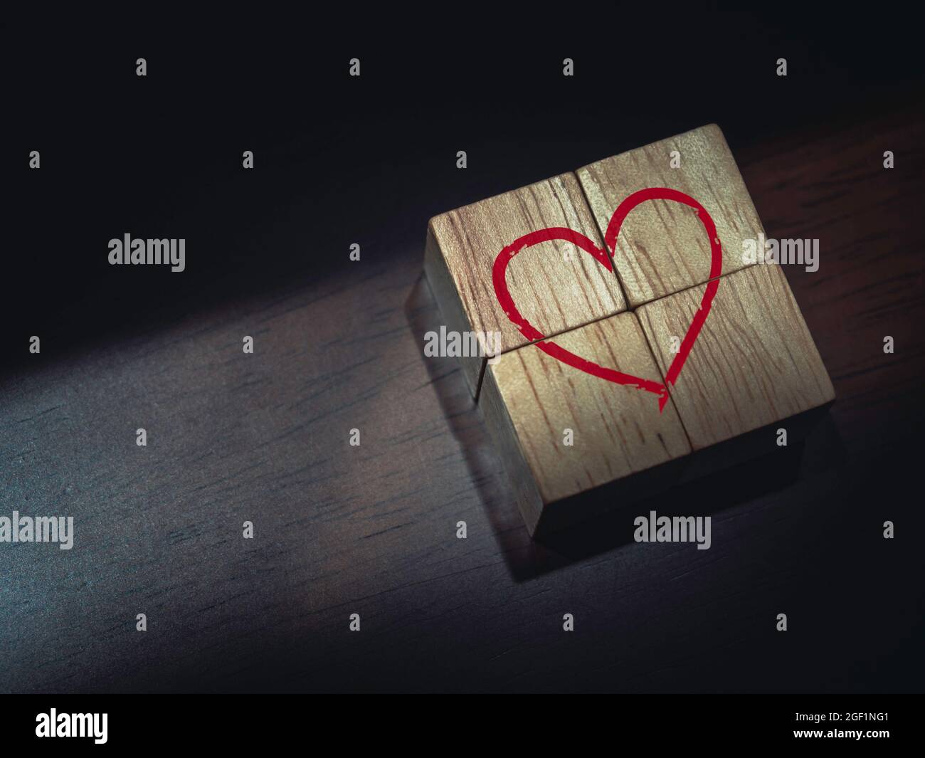 Rotes Herz auf Holzwürfelblöcken auf dunkelbraunem Holzhintergrund. Stockfoto