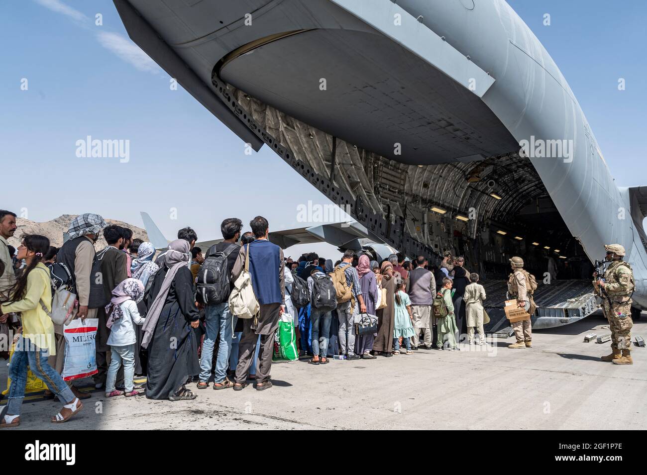 U.S. Airmen und U.S. Marines leiten qualifizierte Evakuierte an Bord einer US Air Force C-17 Globemaster III zur Unterstützung der Evakuierung in Afghanistan am Hamid Karzai International Airport (HKIA), Afghanistan, 21. August 2021. Das Verteidigungsministerium hat sich verpflichtet, das US-Außenministerium beim Ausscheiden von US-amerikanischem und alliiertem Zivilpersonal aus Afghanistan zu unterstützen und die afghanischen Verbündeten in Sicherheit zu bringen. (USA Luftwaffe Foto von Senior Airman Brennen Lege) Stockfoto
