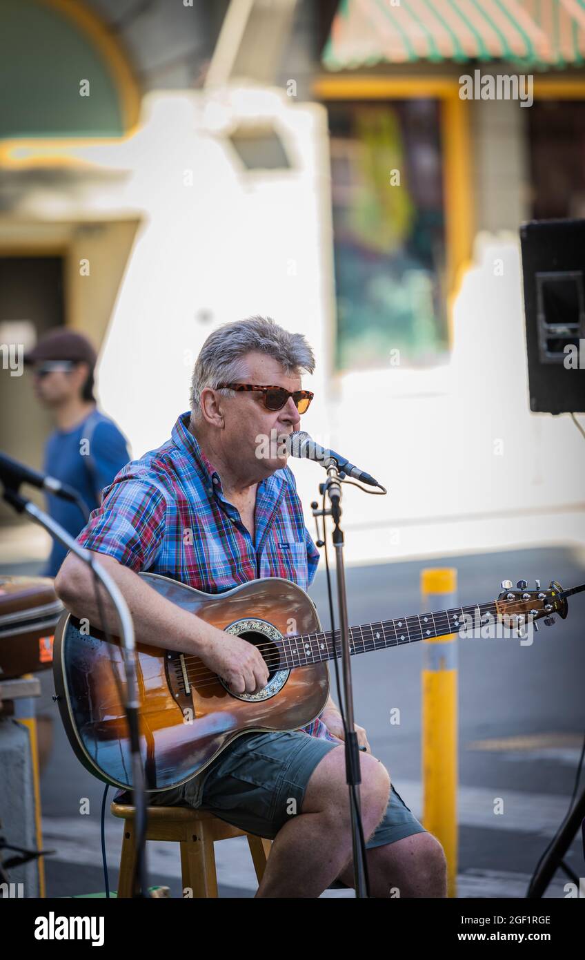 Ein Mann, der Gitarre spielt und auf der Straße der Stadt Lieder singt. Stockfoto