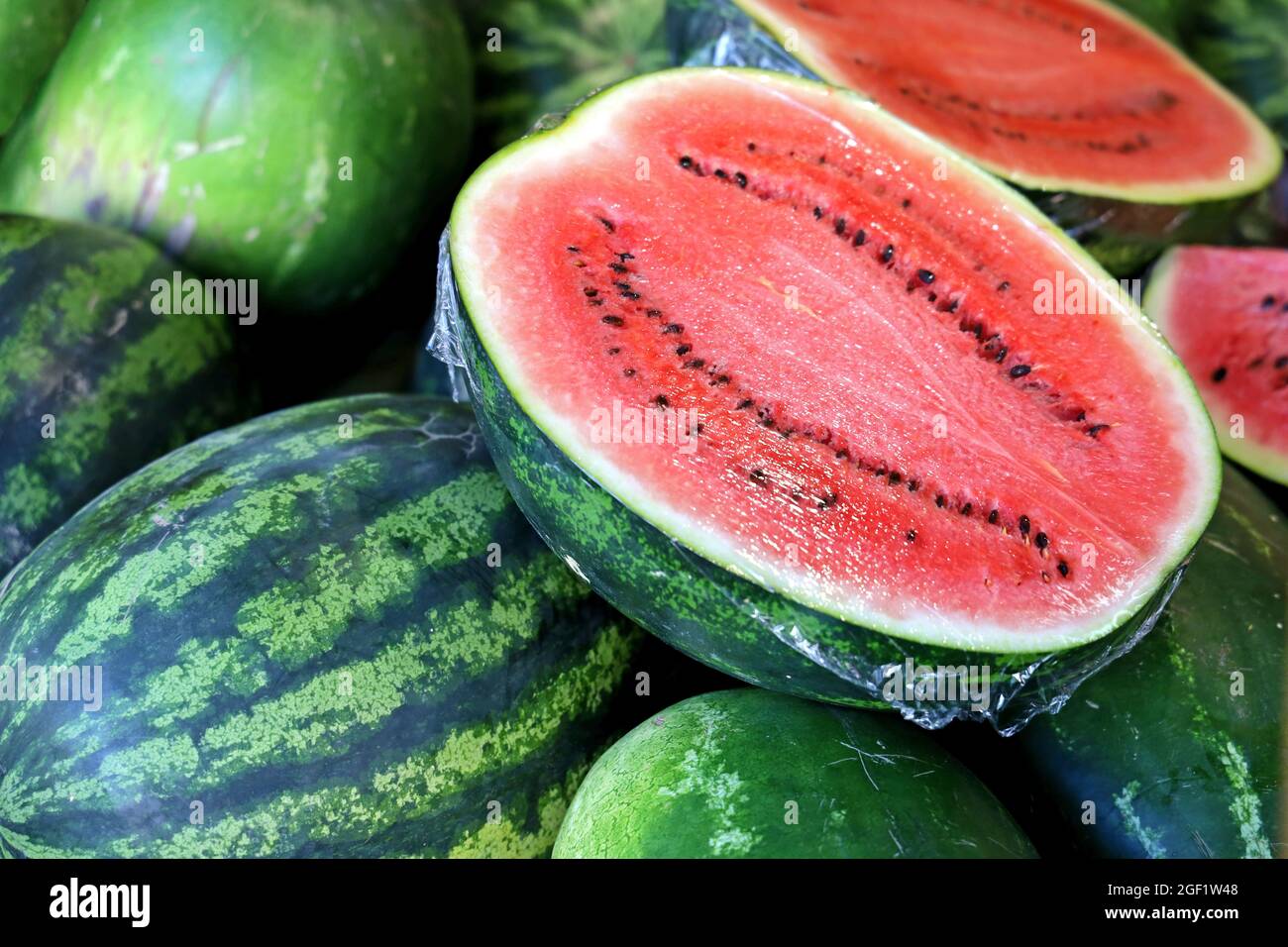 Frische halbierte Wassermelone auf Melonenhaufen zum Verkauf auf dem Lebensmittelmarkt Stockfoto